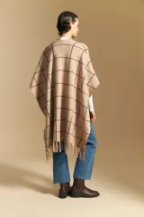 Poncho abierto de tejido de punto con diseño de cuadros grandes en contraste. Presenta un patrón reversible en tonos negro y marrón, con un estilo envolvente y versátil.