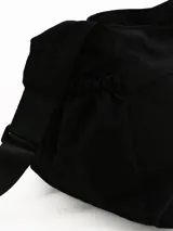 Bandolera de diseño funcional en color marrón, con cierre principal superior y dos bolsillos frontales con tiradores de cuerda. Presenta detalles fruncidos en los laterales y correa ajustable para llevar al hombro o cruzada.