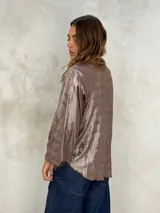 Blusa de manga larga color azul eléctrico con acabado brillante o metalizado, cuello alto y corte holgado.