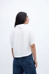 Blusa verde de manga corta con escote en V, cuello camisero y bolsillos en el pecho.