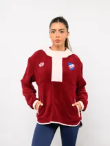 Buzo de micropolar color bordó con capucha, cierre frontal parcial y detalles en color crema. Presenta el logo de Umbro y el escudo del Club Nacional de Football bordados en el frente.