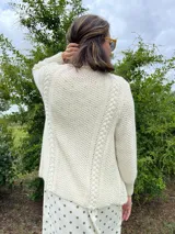 Cardigan tejido a mano color crudo, con solapa en el escote y punto delicado.