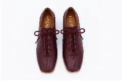 Zapato acordonado de cuero color bordó, con punta cuadrada, costuras frontales visibles y un taco bajo de 3 cm.
