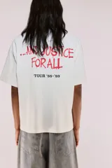 Remera de algodón color blanco crudo, corte oversized y manga corta. Presenta un estampado frontal grande con el logo de Metallica y la ilustración de Lady Justice, con el texto "AND JUSTICE FOR ALL" y "TOUR '83-'89".