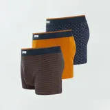 Pack de tres bóxers de algodón para hombre, uno a rayas horizontales azul y marrón, uno liso color ladrillo y uno azul con estampado de puntos marrones. Todos tienen cintura elástica azul.