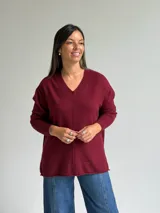 Sweater de punto color bordó, con escote en V, manga larga y costura central vertical decorativa.