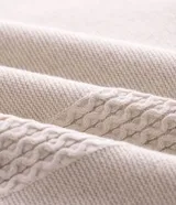 Polo de manga corta confeccionada en tricot liviano, con cuello polo y cierre frontal de cremallera. Presenta un diseño texturizado con detalles trenzados verticales y acabado acanalado.