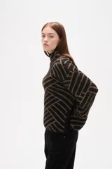 Sweater de tejido jacquard con diseño geométrico de líneas entrelazadas en tonos negro y marrón. Presenta cuello alto, mangas largas con terminación holgada y un corte recto.