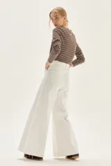 Jean de mujer color blanco, tiro alto, con pierna ancha y corte acampanado. Presenta costuras verticales marcadas en el frente de las piernas.