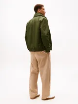 Campera Tommy Hilfiger de color verde militar, con cuello alto, cierre frontal de cremallera y bolsillos laterales. Confeccionada en poliamida, presenta un diseño clásico y versátil con el logo de la marca bordado discretamente en el pecho.