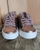 Zapatillas plateadas de cuero con cordones grises y suela blanca.