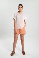 Blusa color blanco de corte holgado, con mangas cortas y detalle de botones en el lateral.