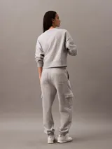 Pantalón de chándal gris de corte holgado con bolsillos cargo laterales, cintura elástica con cordón y bajos elásticos. Confeccionado en felpa de mezcla de algodón.