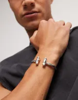 Pulsera rígida plateada de la marca Uno de 50, con dos tubos en los extremos.