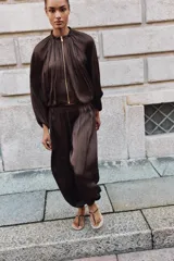 Pantalón de tiro alto con diseño abullonado, confeccionado en tejido satinado con acabado plisado y puños elásticos en los tobillos.