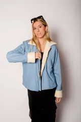 Campera de jean celeste con interior y cuello de corderito color crema, cierre frontal con cremallera y bolsillos laterales.