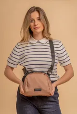 Bandolera de diseño compacto confeccionada en tafeta liviana color beige, con cierre superior y correa ajustable ancha en color negro. Incluye etiqueta de marca frontal.