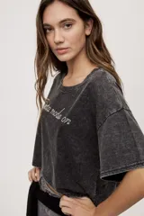 Remera gris de fit amplio, con mangas cortas y cuello redondo. Presenta efecto lavado y estampa frontal con aplicación de strass con la frase "fiesta mode on".
