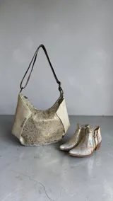 Bota de caña corta de cuero en tonos natural y dorado light, con diseño pintado a mano y puntera fina. Cuenta con taco bloque de madera y doble cierre lateral con tiradores personalizados.