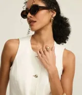 Chaleco largo color crudo confeccionado en sarga de algodón, con cuello redondo, cierre abotonado, bolsillos delanteros y cintura ajustada.