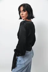 Camisa negra de seda con escote en V cruzado, mangas largas abullonadas y lazos para anudar en el frente.