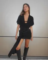 Minifalda negra con drapeado lateral y abertura en la pierna izquierda.