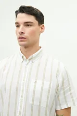 Camisa de manga corta confeccionada en lino y algodón, con fit regular y logo bordado. Color beige con rayas verticales blancas.