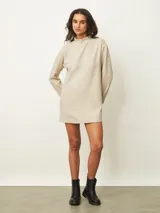 Vestido corto de color beige con cuello alto y mangas largas, de corte recto y holgado.