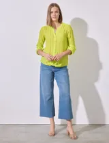 Blusa color amarillo de gasa marca Zac & Rachel, con cuello a la base, escote en V y abertura central con botones. Delantera con bolsillo aplicado. Largo de manga regulable con presilla y botón. Terminación opcional de nudo en ruedo.