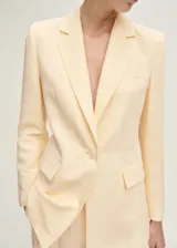 Blazer de corte recto en color amarillo pastel, confeccionado en mezcla de lino y lyocell. Presenta cuello con solapas de muesca, cierre frontal de un botón, bolsillos laterales con solapa y bolsillo de ribete en el pecho.