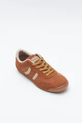 Zapatilla urbana de perfil bajo con diseño retro, confeccionada en poliuretano con detalles en textura tipo gamuza. Presenta puntera redondeada, cordones clásicos y suela de goma color caramelo.