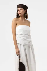 Vestido largo blanco con escote strapless y cuerpo fruncido. Posee falda amplia y fluida con bolsillos.