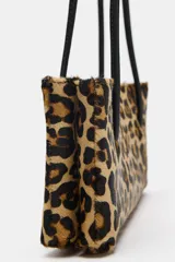 Bolso de hombro de piel con textura y estampado animal print, con doble asa larga negra y compartimento interior con cremallera.