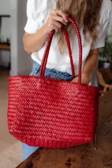 Bolso tipo tote de cuero vacuno, completamente trenzado a mano. El color es marrón oscuro, casi chocolate. Posee dos asas de hombro trenzadas.