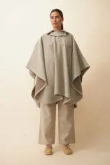 Poncho de lana fina sin teñir, con cuello camisero, cartera con broches a presión y bolsillo ojal. Diseño de estilo campestre con textura tejida.