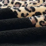 Buzo tipo canguro de polar, con diseño combinado en animal print de leopardo en la parte superior y color gris claro en la parte inferior. Cuenta con capucha, cordones ajustables y cierre frontal.