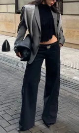 Pantalón de jean estilo wide leg, de tiro bajo y corte recto, en color negro lavado. Presenta costuras reforzadas y diseño de cinco bolsillos.