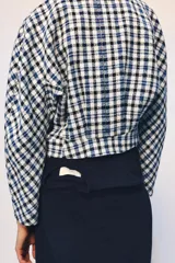 Chaqueta corta de Zara Woman Collection confeccionada en tejido de algodón con estampado de cuadros en tonos blanco, azul y negro. Presenta escote en pico, manga larga y cierre frontal con botones oscuros.