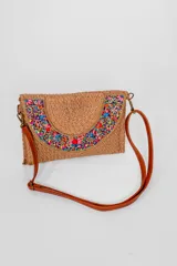 Bandolera de material tejido color marrón, con solapa decorada con canutillos y cuentas multicolores. Incluye correa larga ajustable de cuero sintético.