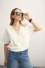 Blusa blanca con diseño cruzado, escote en V y mangas cortas.