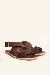 Sandalias bajas de cuero negro con tachas plateadas, tiras cruzadas y hebilla al tobillo.