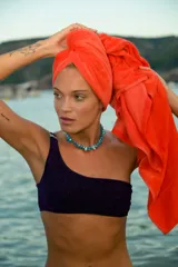 Bikini de tela lúrex color violeta con acabado brillante. El corpiño es tipo top de un solo hombro con hebilla metálica decorativa en el tirante. La bombacha es de corte vedetina.