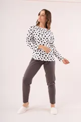Pijama de dos piezas, compuesto por una remera de manga larga blanca con lunares negros y un pantalón largo gris.