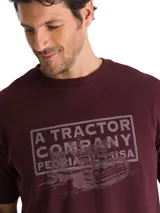 Remera de algodón color bordó con cuello redondo y manga corta. Presenta un gráfico estampado en el pecho con la leyenda A TRACTOR COMPANY PEORIA IL USA y una ilustración de maquinaria pesada.