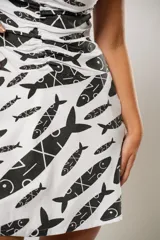 Vestido corto blanco con estampado de peces negros, corte ajustado, escote halter y falda evasé.