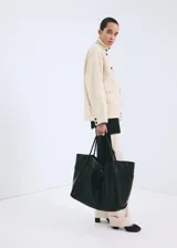 Chaqueta de algodón estilo denim, de diseño oversize, color beige, con cuello alto, manga larga, bolsillos de parche con solapa y cierre frontal de botones oscuros.