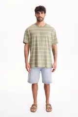 Remera oversize de manga corta confeccionada en 100% algodón, con diseño a rayas horizontales en tonos verde y blanco.