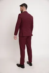 Traje de dos piezas color bordó, compuesto por saco de corte slim fit con solapa clásica, cierre de un botón y bolsillos laterales, y pantalón de vestir a juego de corte recto.