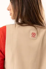 Chaleco de corte sastre en color beige, con escote en V, cierre frontal mediante botones y costuras decorativas en contraste.