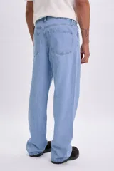 Pantalón jean de corte holgado y tiro medio, en color azul claro, con diseño clásico de cinco bolsillos y pespuntes en contraste.